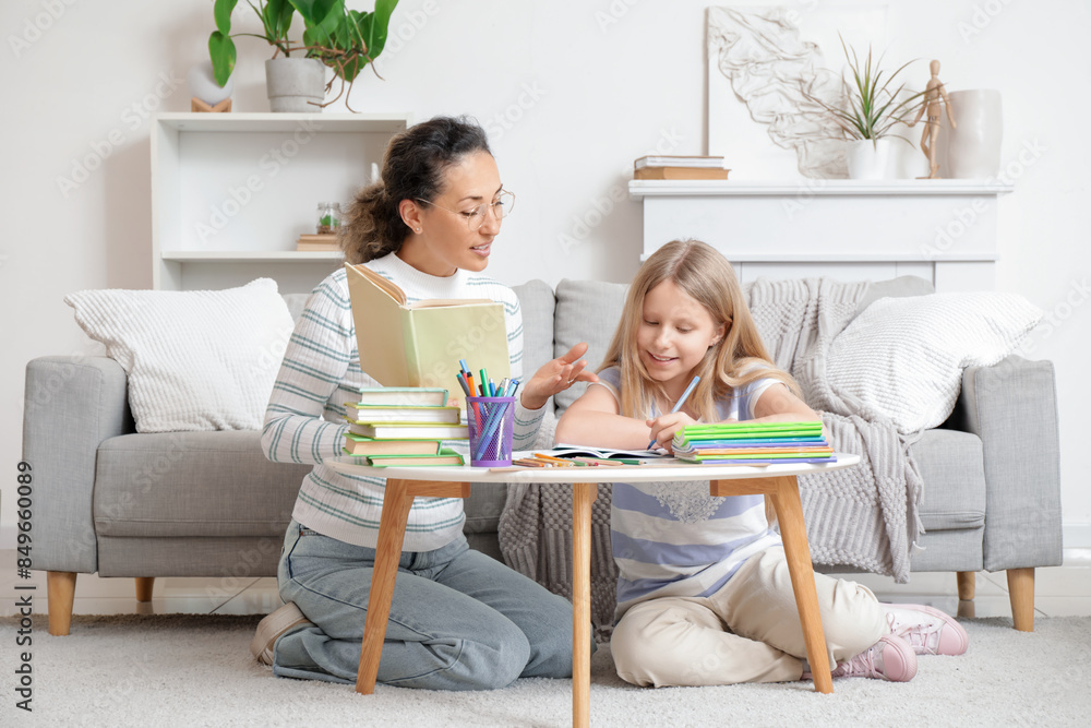 Female tutor with book giving lesson to little girl at home Female tutor with book giving lesson to little girl at home