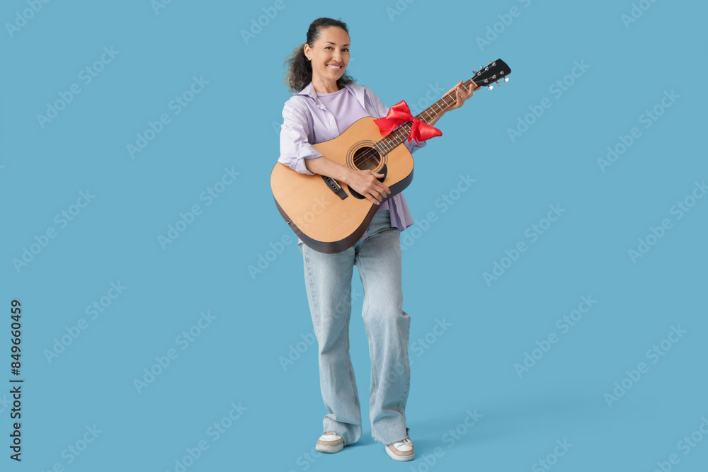 Mature woman with gift guitar on blue background Mature woman with gift guitar on blue background