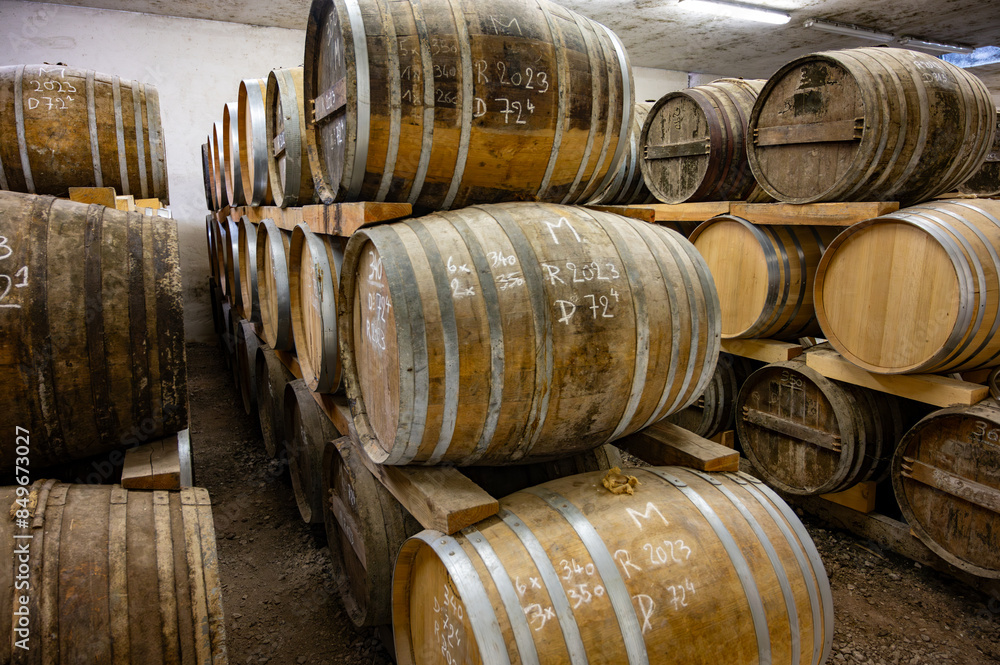 Aging process of cognac spirit in old dark French oak barrels in cellar in distillery house, Cognac white wine region, Charente, Segonzac, Grand Champagne, France Aging process of cognac spirit in old dark French oak barrels in cellar in distillery house, Cognac white wine region, Charente, Segonzac, Grand Champagne, France