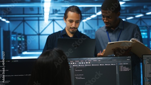 Man inspecting server hub infrastructure, reading paperwork from folder, talking with workers. Supervisor doing evaluation of data center facility workspace, verifying documents photo