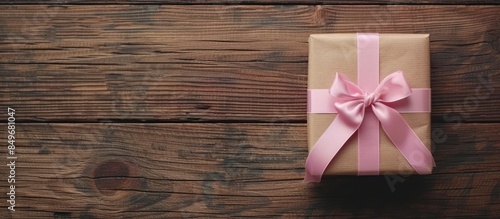 Gift box with pink ribbon on wooden table