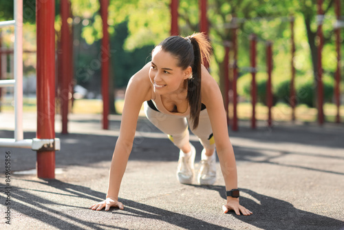 Pretty young woman in sportswear exercising on sport ground