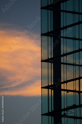Stimmungsvolle Detailaufnahme einer modernen Glasfassade in München bei Sonnenuntergang mit Wolken