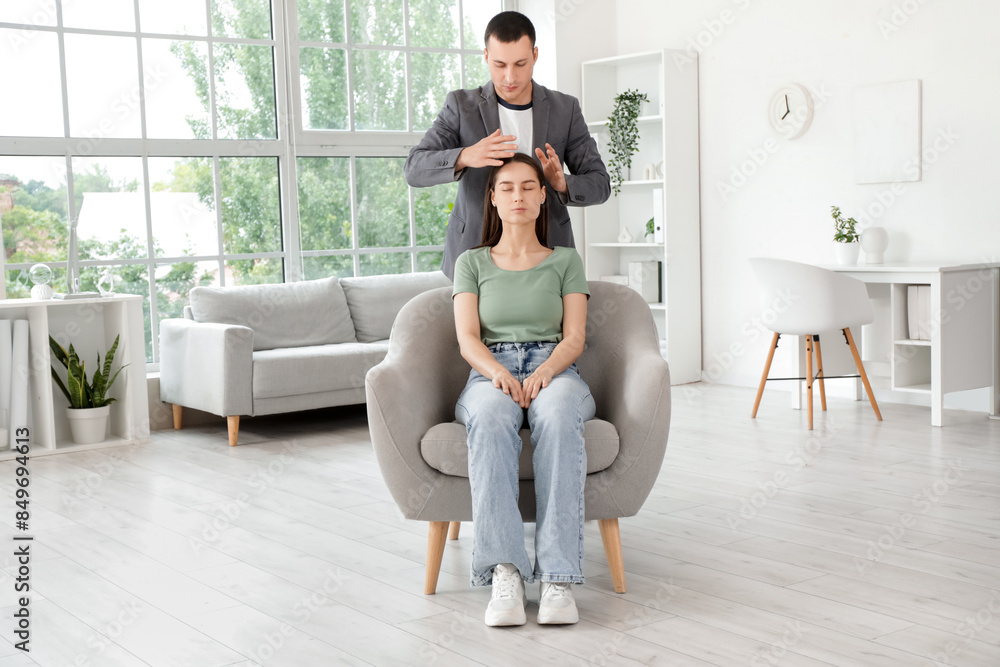 Obraz premium Young woman sitting in armchair during hypnosis session at psychologist office
