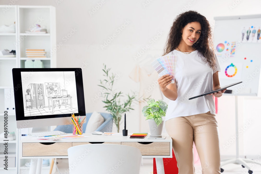 Female African-American graphic designer with tablet and color palettes in office Female African-American graphic designer with tablet and color palettes in office