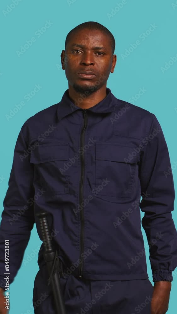 Vertical video Security guard doing salute hand gesture, preparing to start job of deterring criminals. Portrait of bodyguard doing greeting gesturing and military pose, studio background, camera B Vertical video Security guard doing salute hand gesture, preparing to start job of deterring criminals. Portrait of bodyguard doing greeting gesturing and military pose, studio background, camera B