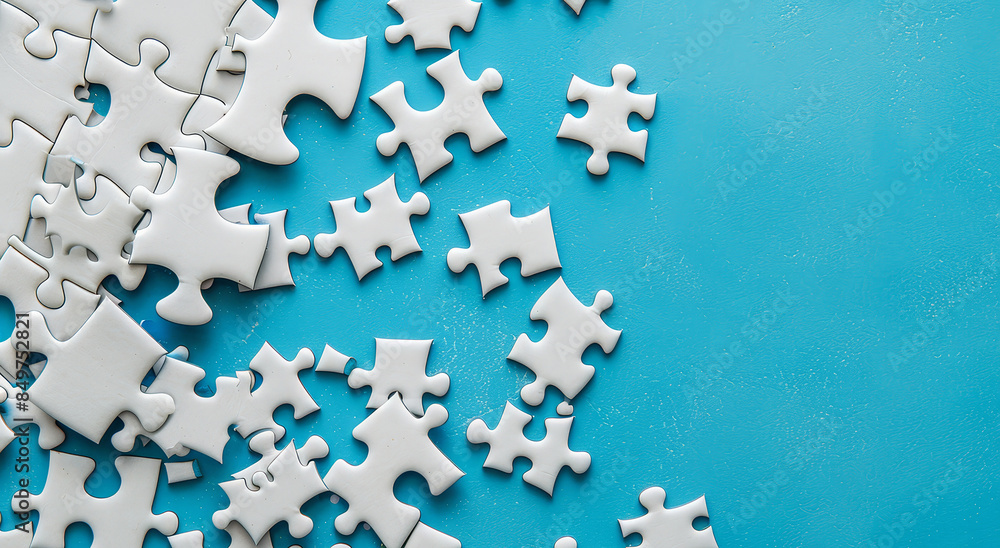 Fragment of a folded white puzzle and a pile of unkempt puzzle pieces on a blue surface background with copy space.
