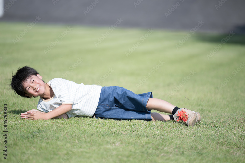 芝生に寝転がる笑顔の男の子のカメラ目線 芝生に寝転がる笑顔の男の子のカメラ目線