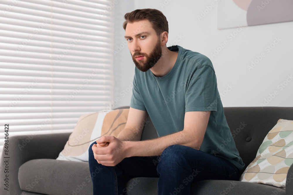 Loneliness concept. Sad man sitting on sofa at home Loneliness concept. Sad man sitting on sofa at home