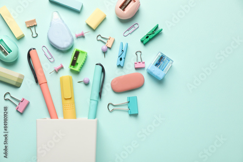 Flat lay composition with holder and different stationery on turquoise background, space for text