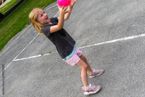 Young Girl Playing With Pink Ball on a Sunny Day