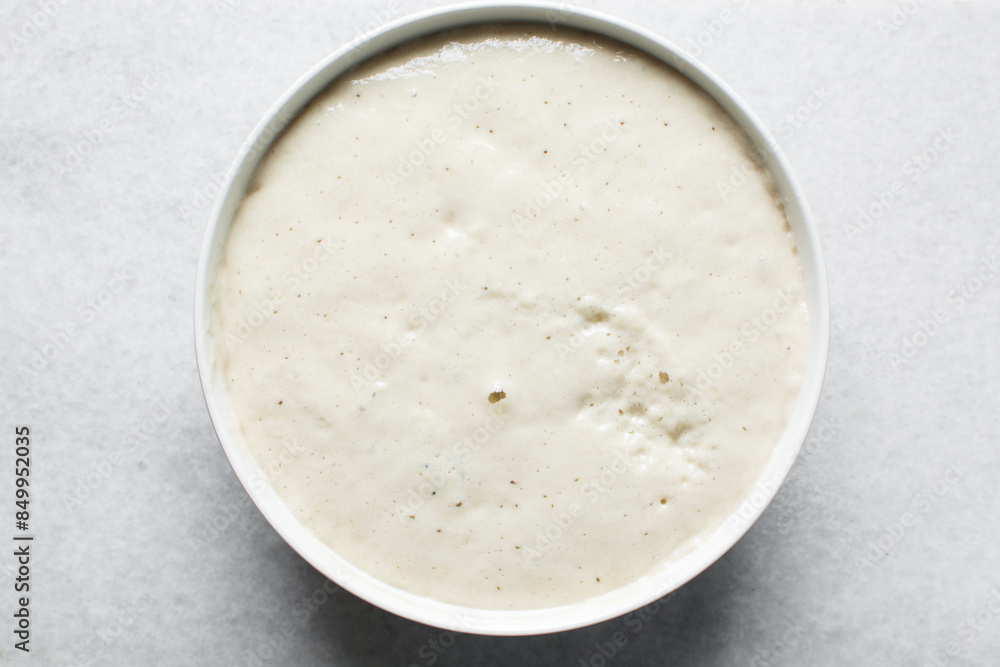 Overhead view of nigerian puff-puff dough that has proofed, puff-puff dough in a white mixing bowl, process of making puff-puff or bofrot Overhead view of nigerian puff-puff dough that has proofed, puff-puff dough in a white mixing bowl, process of making puff-puff or bofrot