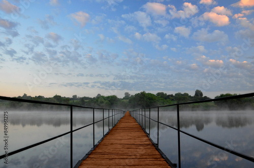 Wallpaper Mural Long bridge crossing the river or lake. Wooden old bridge perspective in early morning with blue sky & clouds. Nature panoramic amazing wild landscape and river bridge as walkway or path background Torontodigital.ca