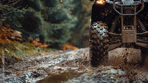 An ATV's journey through a dense, muddy forest trail, wheels spinning, mud splattering, trees and foliage in the background photo