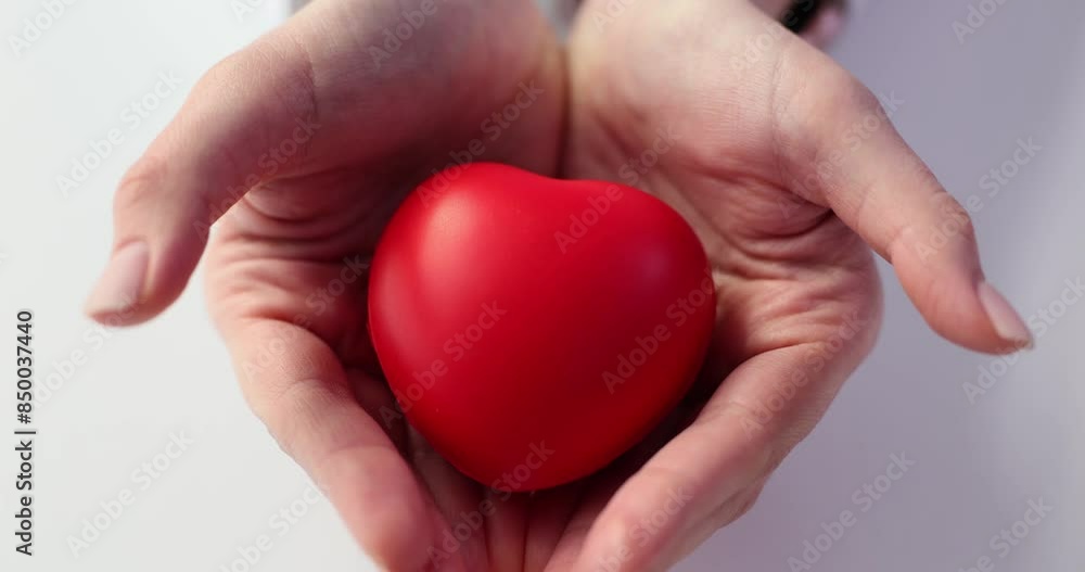 Lady opens hands showing heart toy on white background Lady opens hands showing heart toy on white background