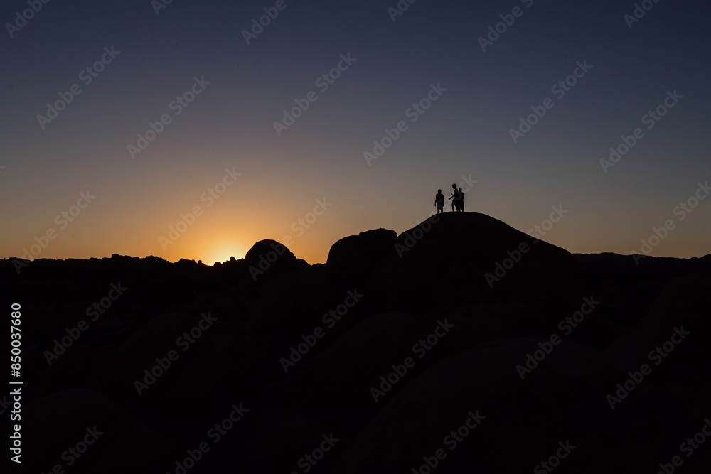 Silouette of poeple standing on giant boulders in Joshua Tree National Park, California, United States of America. Silouette of poeple standing on giant boulders in Joshua Tree National Park, California, United States of America.