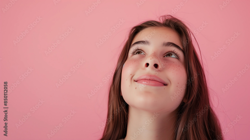 photo of a happy teenage girl with straight brown hair looking up an smiling on a pink pastel background. Happiness and youth concept photo of a happy teenage girl with straight brown hair looking up an smiling on a pink pastel background. Happiness and youth concept