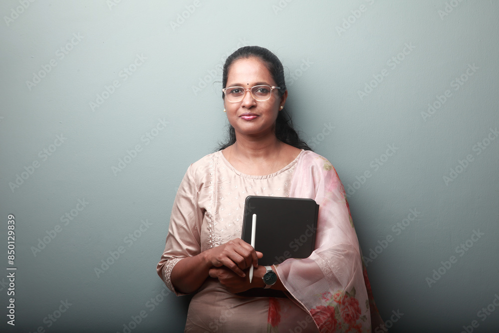 Portrait of a woman of Indian ethnicity with a smiling face holding a tablet computer in hand Portrait of a woman of Indian ethnicity with a smiling face holding a tablet computer in hand