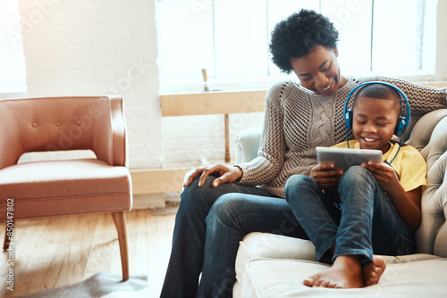 Tablet, mother and boy with headphones on sofa for digital media, streaming service and bonding. Happy, black family and kid with tech at home for online movie, connectivity and network subscription