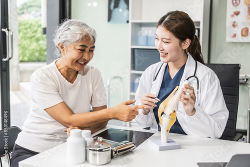 A young Asian female nurse providing healthcare services at her desk, caring for an elderly woman patient. They discuss health checklists and medical advice in a professional setting. © NanSan