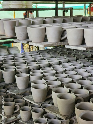Showcasing an array of unfinished pottery ceramic pieces, meticulously arranged on workshop shelves. Captures various sizes and stages of the crafting process. Ideal for art, craft, and pottery.