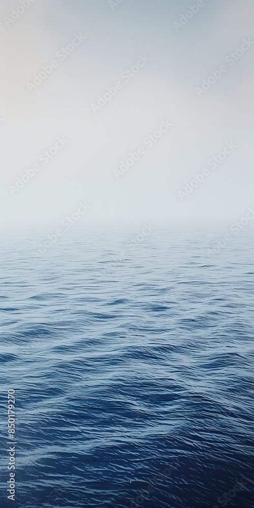 Obraz premium The ocean is calm and peaceful, with a few clouds in the sky