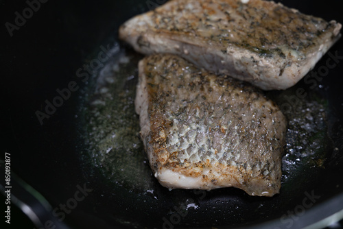 Fresh sea bass marinated with spices and fried with butter in a black iron pan.