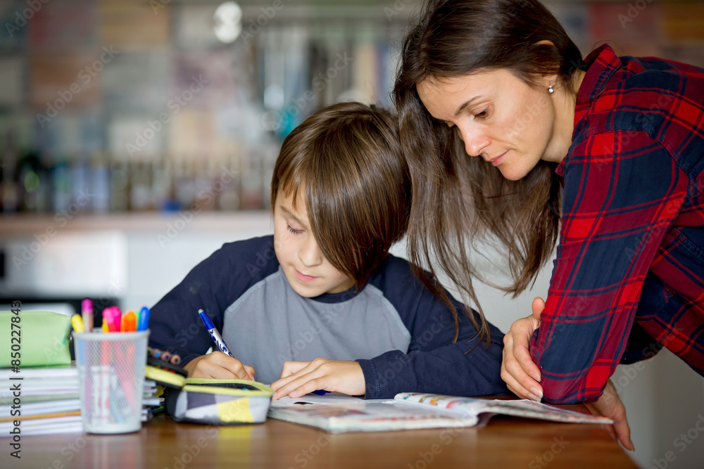 Mother, helping her child with homeworks, kid learning at home during pandemic Covid lockdown Mother, helping her child with homeworks, kid learning at home during pandemic Covid lockdown