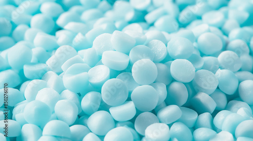 Close-up of many small, light blue plastic pellets, highlighting their uniform shape and smooth texture.
