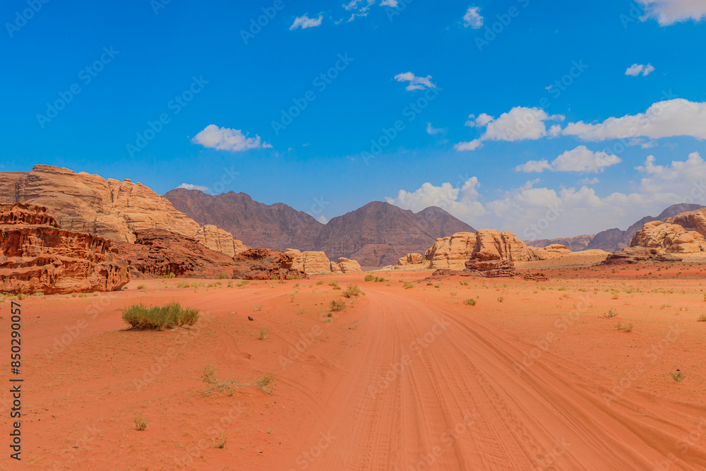 Panoramic view of the stunning desert scenery in Wadi Rum, Jordan, showcasing vast sandy expanses and towering rock formations under a bright blue sky Panoramic view of the stunning desert scenery in Wadi Rum, Jordan, showcasing vast sandy expanses and towering rock formations under a bright blue sky