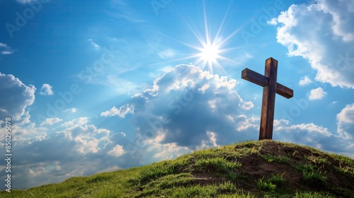 wooden cross on grass hill with sun and blue skies, copy space
