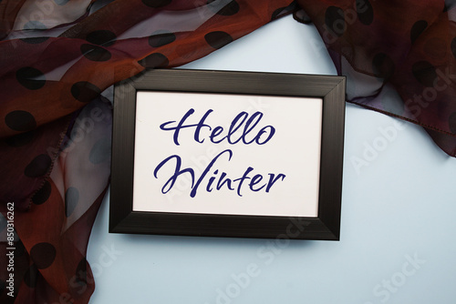 Hello Winter text message with scarft on blue background photo