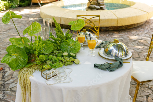 a beautifully served table for two decorated with flowers in a shady courtyard near the fountain photo