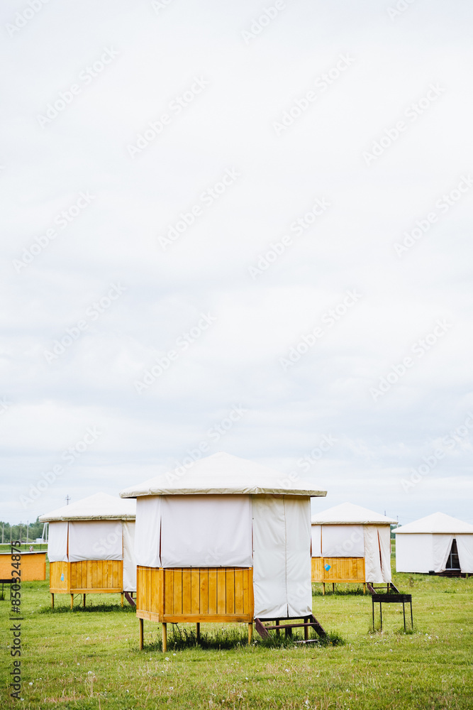 Small tents are set up in a grassy field under a clear sky, providing a scenic view of the horizon and vast meadow. The scene radiates a sense of peace and the beauty of nature Small tents are set up in a grassy field under a clear sky, providing a scenic view of the horizon and vast meadow. The scene radiates a sense of peace and the beauty of nature