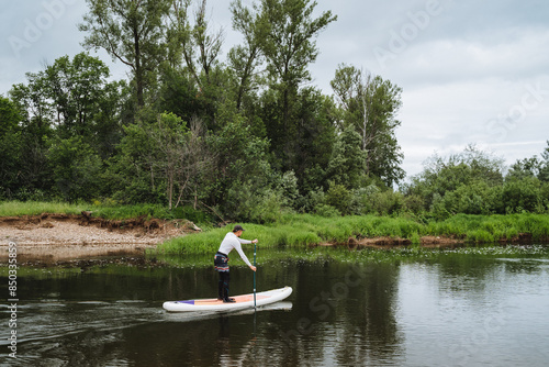 Enjoy a peaceful paddleboarding experience on a tranquil river, surrounded by lush greenery. Perfect for nature lovers seeking a serene outdoor adventure in beautiful landscapes