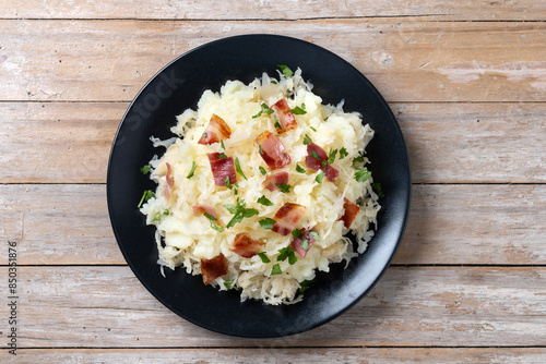 Slovak potato dumplings halusky with steamed sauerkraut and bacon on wooden table. Top view photo