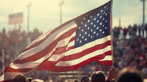 American flag being flown at a sporting event, with fans cheering and waving their flags.