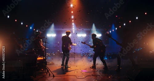 Young Indie Band Playing a Rock Music Gig with Alternative Punk Tracks at a Festival with Energetic Music Fans. Five Charismatic Musicians Make a Live Performance Under Falling Confetti photo