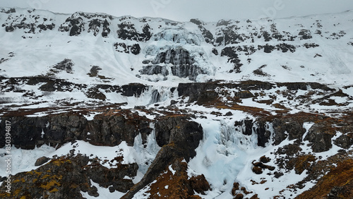 The magnificent Dynjandi waterfall in Iceland is covered in a stunning blanket of ice and snow, creating a truly breathtaking sight