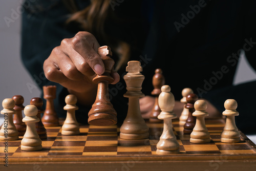 Businesswoman moving a chess piece on chess board. Business competition strategy and management concept
