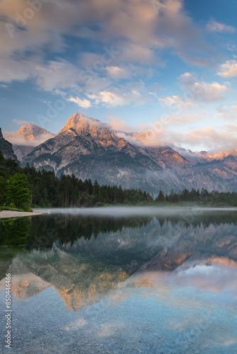 This stunning image captures the beauty of Almsee Lake in Austria. The calm waters reflect the surrounding mountain peaks, creating a breathtaking scene. 
