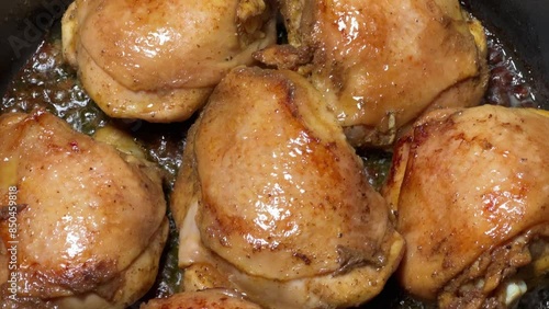 Frying chicken thighs in hot cooking oil on frying pan photo