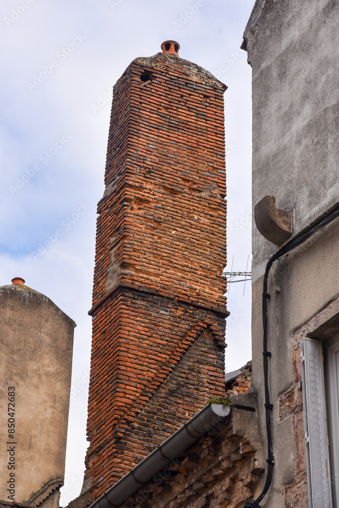 Old brick chimney tower on the roof of an old french house
