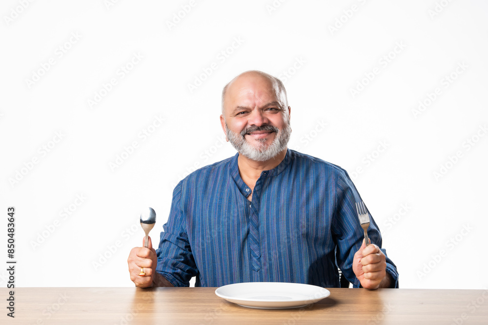 Concept showing Indian asian retired senior old man with empty ceramic plate, holding, presenting or pointing Concept showing Indian asian retired senior old man with empty ceramic plate, holding, presenting or pointing