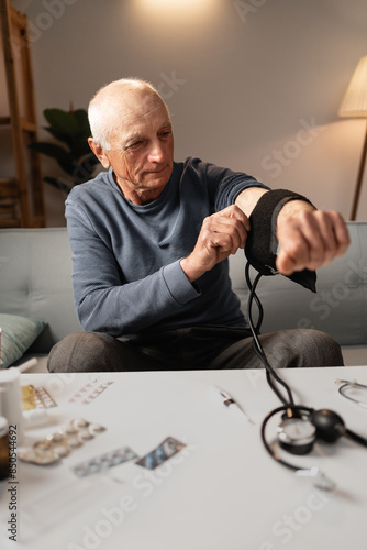 Elderly man using a sphygmomanometer to measure blood pressure at home