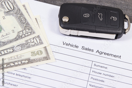 Car key, dollar banknotes and form of vehicle sales agreement. Sales or purchases new or used vehicle