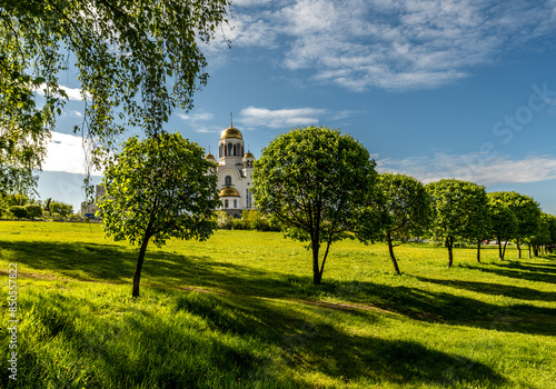 A church with golden domes in summer among green trees.