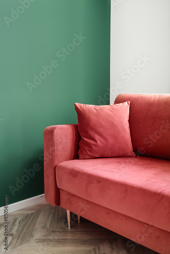 Comfortable sofa with soft decorative pillow in living room with green wall