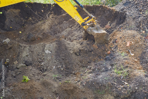 The excavator bucket digs hard soil and rocks