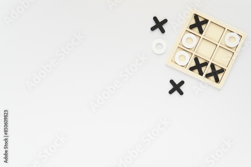 Wooden black and white tic-tac-toe board game on white background, competition, kids activity, brain games concept, free space for text.